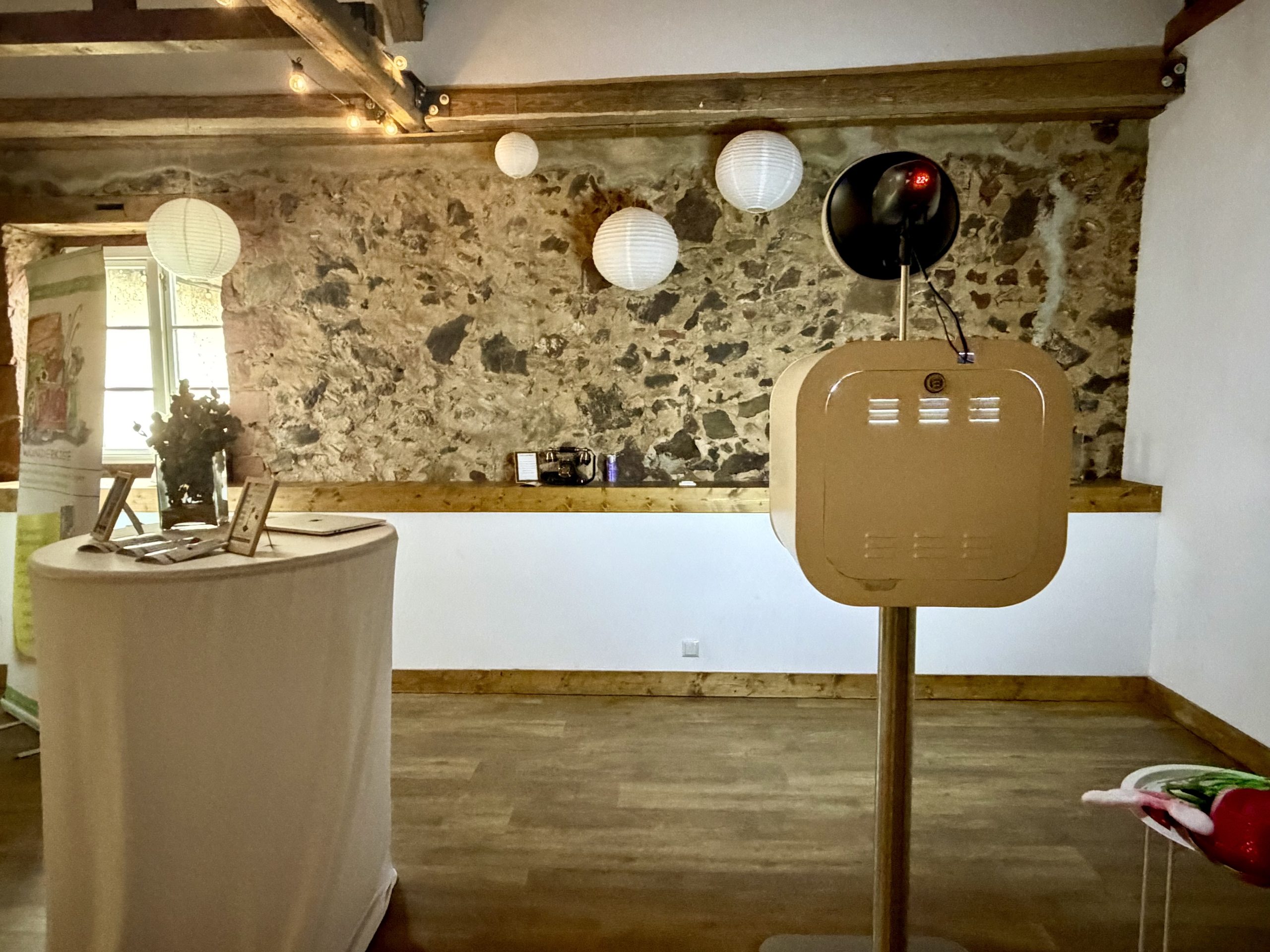 Fotobox Lite mit Studioblitz vor einer Natursteinwand mit weißen Lampions in der Obermühle Langenselbold