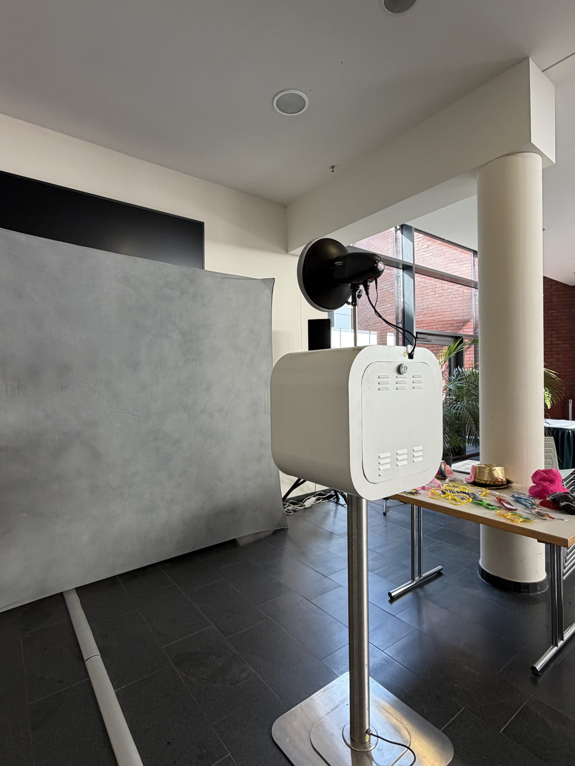 Fotobox Lite mit Studioblitz und Accessoires vor einem grauen Fotohintergrund