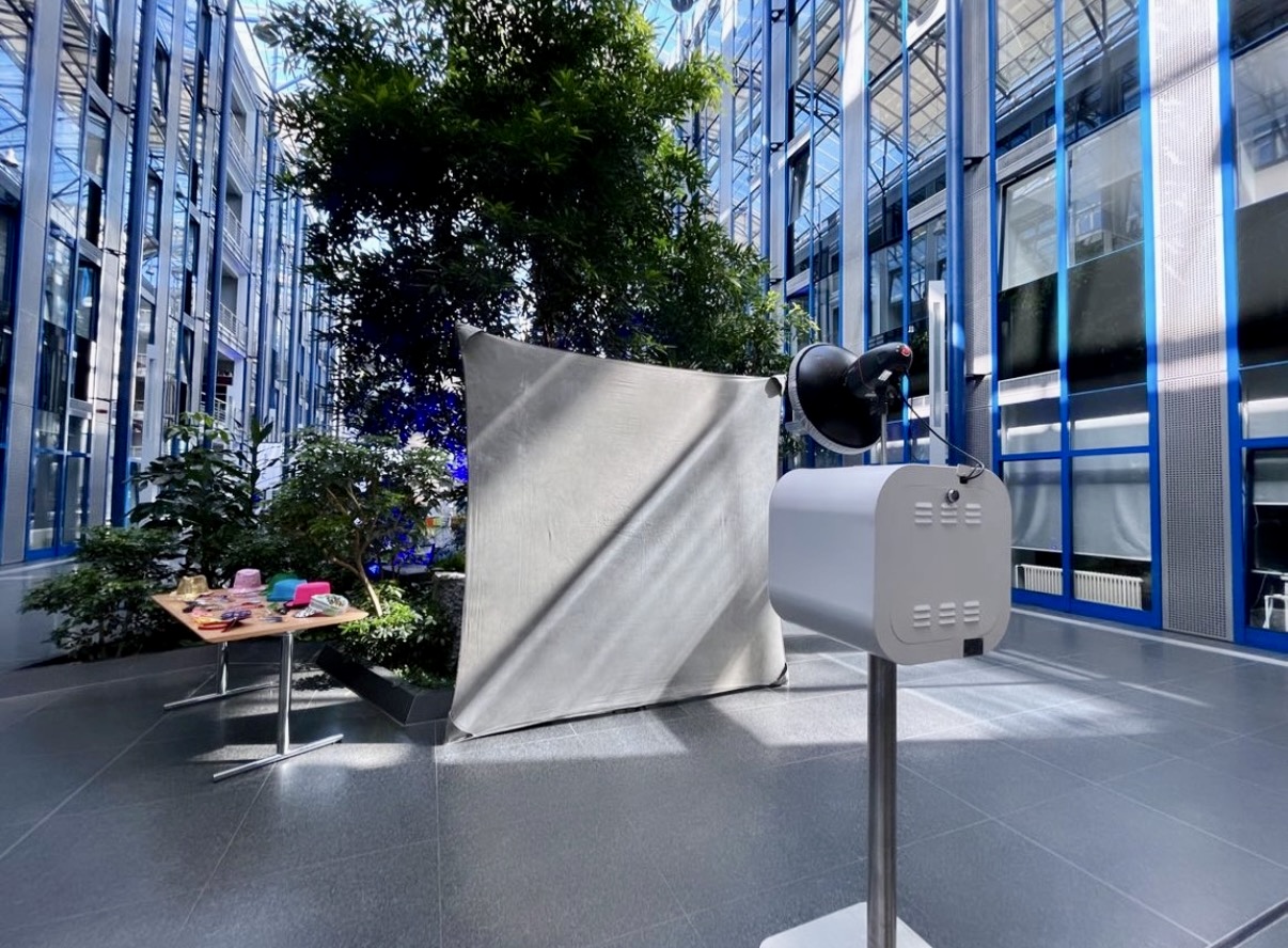 Fotobox Lite mit Studioblitz, weißem Hintergrund und Accessoires-Tisch in einem lichtdurchfluteten Atrium