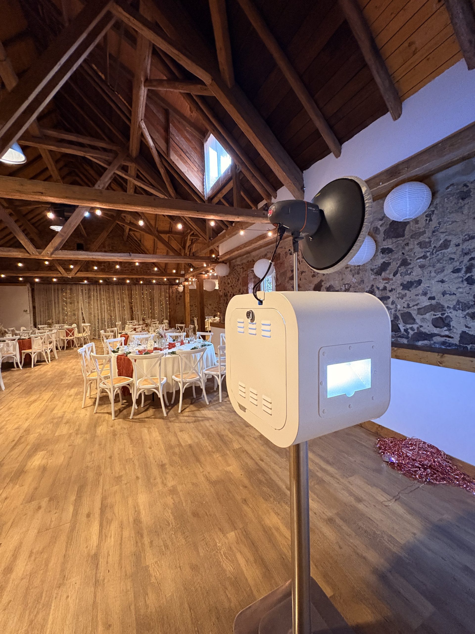 Fotobox Lite neben festlich gedeckten Tischen unter Holzbalken und Lichterketten in der Obermühle Langenselbold